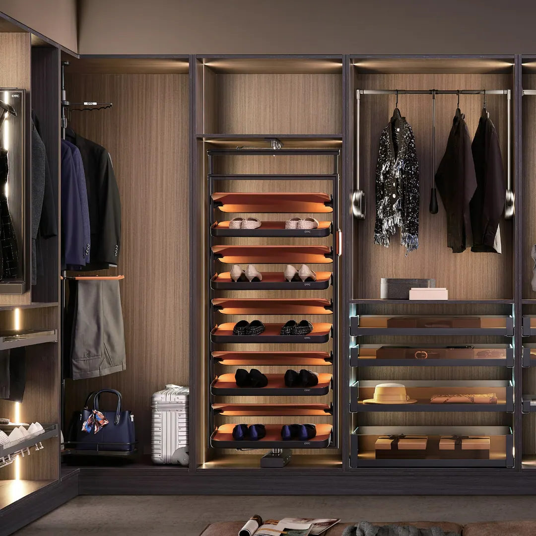 A Wald walk-in closet in dark woodgrain: lit shoe shelves, a pull-down hanging rail and wire accessory baskets